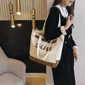 Detail view of the canvas shoulder bag with SUN print and contrasting brown leather trim