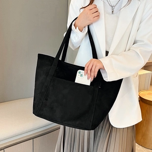Detailed shot of a black PU tote bag showing a white smartphone placed in the front pocket