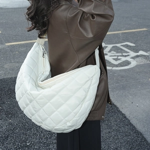 Vue de rue d'un sac bandoulière blanc en nylon matelassé au design bouffant