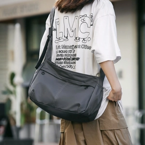 Detailed view of dark grey nylon crossbody bag with adjustable wide strap and seam details