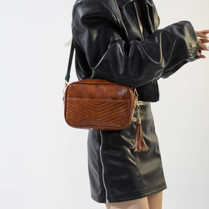 Detail of vintage brown bag featuring V-shaped stitching and a boho patterned strap