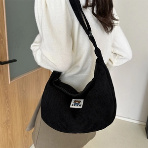 Detail of black corduroy half-moon crossbody bag with cute MF BEAR cartoon patch