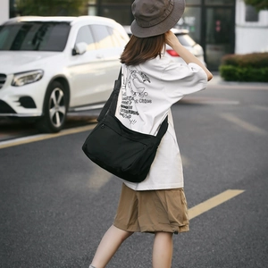 Detail view of black nylon messenger bag with adjustable wide strap and zipper closure