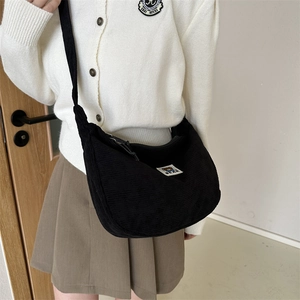 Close-up of black corduroy moon-shaped crossbody bag with cute bear patch detail