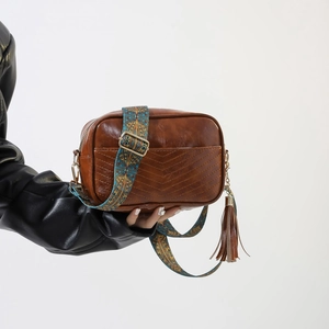 Detail of vintage brown shoulder bag with V-shaped stitching and ethnic woven strap