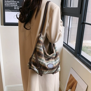 Détail du sac cabas en laine montrant la texture rayée verte et la bandoulière en cuir