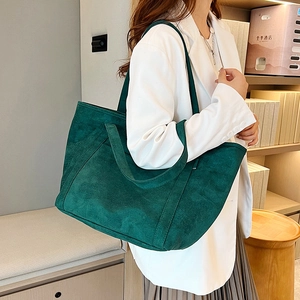 Detailed side view of deep green suede tote bag with reinforced stitching on shoulder strap