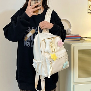 Détail du mini sac à dos en nylon crème avec pendentifs étoiles en peluche et cordons