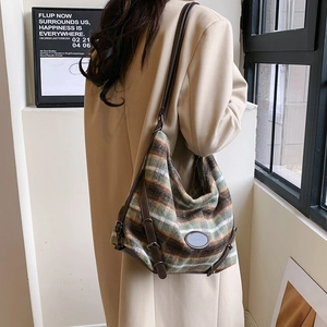 Détail d'un sac cabas en toile rayée rétro avec anses en cuir brun dans un cadre de vie