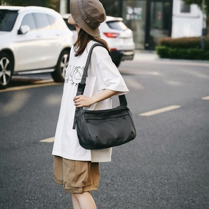 Outdoor shot of a woman wearing a black waterproof nylon crossbody messenger bag on street