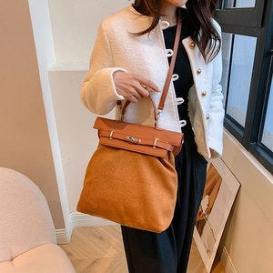 Detail of orange-brown suede patchwork handbag with metal twist lock and shoulder strap