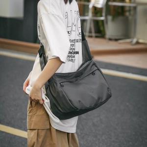 Detail of dark grey nylon crossbody bag with multi-zipper compartments and adjustable strap