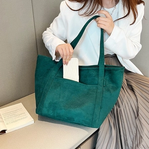 Detail of dark green matte tote bag featuring a functional front pocket and large capacity