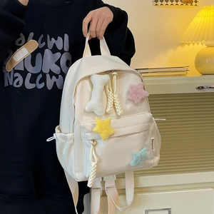 Détail d'un sac à dos en nylon blanc crème avec étoiles en peluche et cordon de serrage
