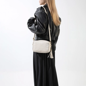 Vue détaillée d'un sac à bandoulière beige avec long gland et chaîne dorée sur un mannequin