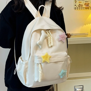 Détail d'un sac à dos blanc en nylon avec des étoiles en peluche et un charme en os