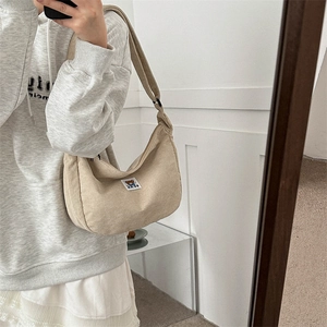 Close-up of beige corduroy hobo bag featuring a cute bear patch and ribbed texture