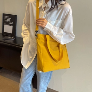 Détail d'un sac cabas jaune vif imperméable avec de larges bandoulières et crochets