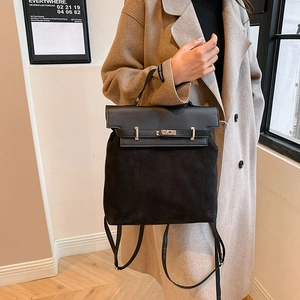 Detail of premium black PU and suede patchwork handbag with classic metal lock and straps