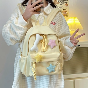 Détail d'un sac à dos en nylon jaune clair avec étoiles en peluche et breloque en os