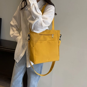 Sac bandoulière jaune imperméable porté avec une chemise blanche et un jean clair