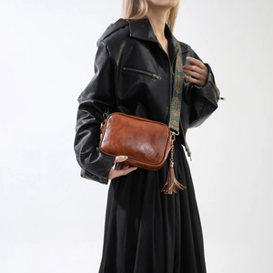 Sac oreiller en cuir marron vintage avec bandoulière jacquard porté par un modèle