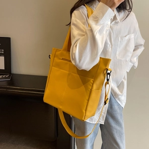 Détail du sac bandoulière en nylon jaune résistant à l'eau porté par un mannequin