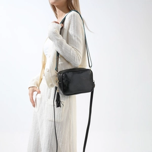 Détail du sac sous le bras en PU noir avec bandoulière ethnique tissée et pompon décoratif
