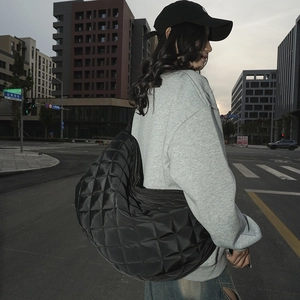 Détail d'un sac bandoulière en nylon matelassé noir avec motif à carreaux et bandoulière