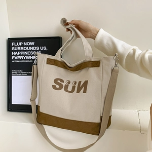 Detail of canvas tote bag showing the SUN graphic and brown patchwork bottom trim