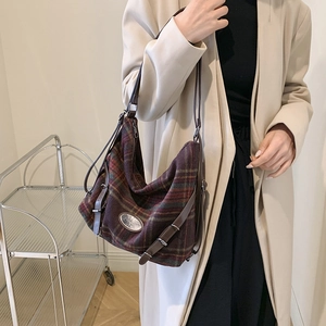 Vue détaillée du sac à bandoulière en laine à carreaux avec emblème en métal et sangle en cuir