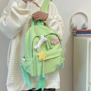 Détail du sac à dos en nylon vert clair avec des breloques pelucheuses en forme d'étoile