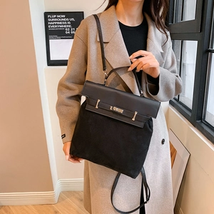 Detail of minimalist black leather and suede bag with silver turn-lock and adjustable strap