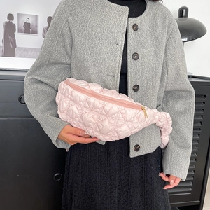 Sac bandoulière matelassé rose avec texture nuage et fermeture dorée sur modèle