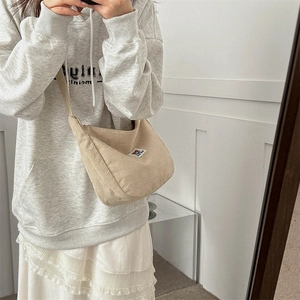 Detail view of beige corduroy half-moon crossbody bag with cute bear fabric label