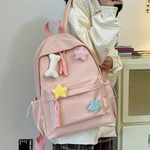 Détail d'un sac à dos en nylon rose avec des breloques en peluche et un décor d'os