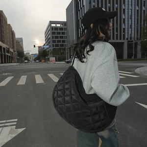 Vue de rue d'une femme portant un sac en nylon noir matelassé en forme de croissant