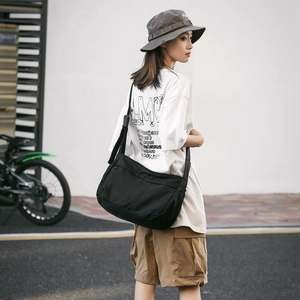 Detailed view of the black nylon messenger bag featuring adjustable strap and sleek pockets
