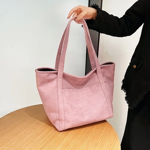 Detailed texture of a soft pink suede tote bag with decorative front pocket design