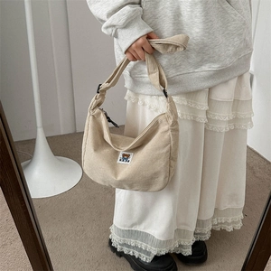 Detail of beige corduroy half-moon crossbody bag featuring a cute bear patch
