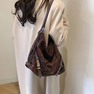 Détail du sac à bandoulière en laine à carreaux marron avec sangle en cuir sur manteau beige