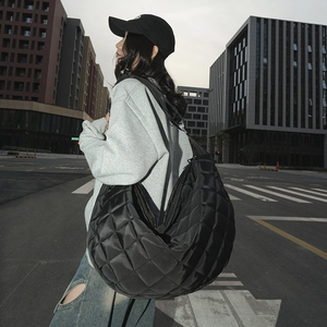 Photo de rue d'un sac demi-lune en nylon noir matelassé porté en bandoulière par un mannequin