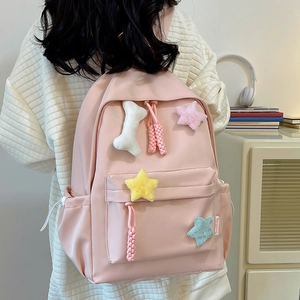 Détail d'un sac à dos rose en nylon avec charms d'étoiles en peluche et poche latérale