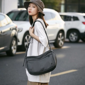 Detail view of durable charcoal nylon crossbody bag with adjustable strap and zip layers