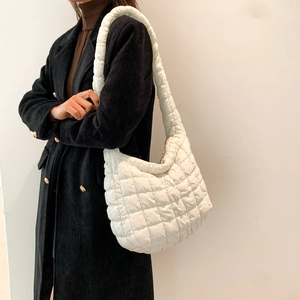 Close-up of a white quilted puffer bag with unique bubble texture on black coat
