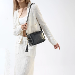Vue détaillée du sac bandoulière en cuir noir avec de longues franges et fermeture éclair dorée