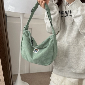 Detail of light green corduroy bag with cartoon bear patch and adjustable strap