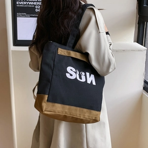 Minimalist black and khaki canvas tote bag with SUN print carried by a model