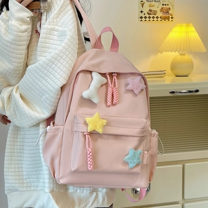 Détail du sac à dos en nylon rose avec étoiles en peluche et pendentif en os
