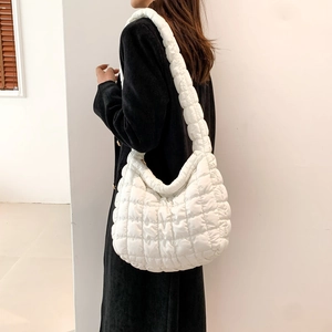 Detailed view of white quilted puffer shoulder bag with padded strap on a model